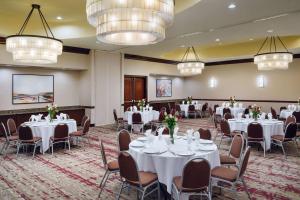 埃尔帕索埃尔帕索机场希尔顿花园酒店的宴会厅配有白色的桌椅和吊灯。
