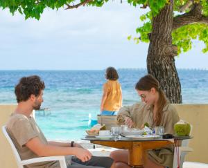 妮兰朵南环礁Villa Stella, Rinbudhoo的坐在海滩桌子上的男人和女人