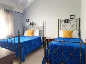 PrioryIsle Be Back Villa的卧室内的两张床,配有蓝色的床单和黄色的枕头