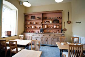 阿伯里斯特威斯Plas Nanteos Mansion的一间设有桌子和陶器架子的用餐室