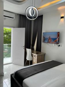 哈科特港HighX Hotels的一间卧室配有一张床、一张书桌和一台电视。