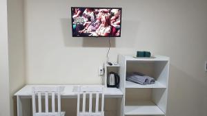埃斯特城España Confort 2的一张带两把椅子的白色书桌和墙上的电视