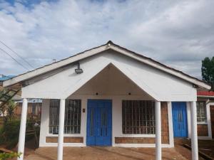 KisiiA Lovely smart family guest house的白色和蓝色的建筑,设有蓝色的门