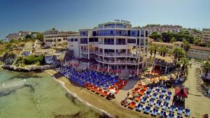 库萨达斯Ladies Beach Suite Hotel的海滩上的酒店,配有椅子和遮阳伞