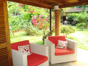 塔卡马卡Coté Sud - Unique Villa & Bungalows Intendance Road的门廊上设有两把椅子,享有花园的景色