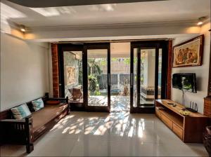 KetewelGriya Umadui Bali的带沙发和滑动玻璃门的客厅