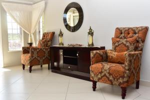 格拉罕镇Villa Palesa Guesthouse的客厅配有两把椅子和镜子