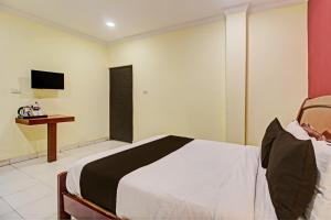 海得拉巴Hotel Ruma Near Nampally Railway Station的一间卧室配有一张床、一张书桌和一台电视