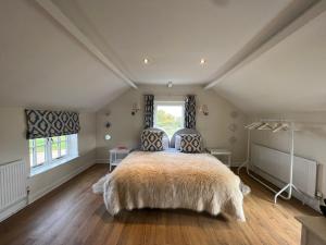 雷克瑟姆Luxury homely open-plan Barn with log burner & games room的一间卧室设有一张大床和一个窗户。