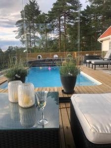 索恩Leilighet i Sørlandshus i Son - Sjøutsikt - Nær Son Spa的一杯酒在泳池旁的桌子上