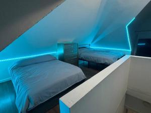 PassaicNYC Gateway: Cozy Home with Easy Access的蓝色灯光客房内的两张床