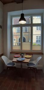 吕贝克Ferienwohnung Kontor im Traufenhaus的餐桌、两把椅子和窗户