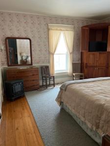 拉特兰Antique Mansion B & B的一间卧室配有一张床、梳妆台和镜子