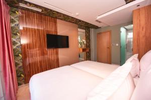 纳祖尔MAGNIFIQUE HOTEL的卧室配有白色的床和平面电视。