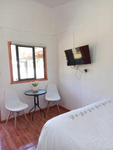 柯纳里佩Alojamiento Ximena的一间卧室配有一张床、一张桌子和两把椅子