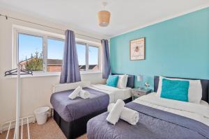 KentBridgeCity Luxurious Maidstone Holiday Home的配有两张床铺的蓝色墙壁和窗户