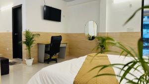 诺伊达Hotel Relax In - Noida Sector 18的一间卧室配有书桌、一张床和一把椅子