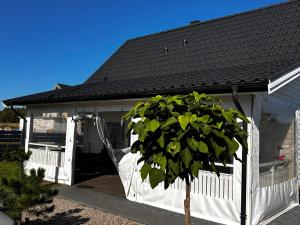 吉日茨科Domek Całoroczny Fuleda -Mazury Giżycko Sauna Jacuzii Kominek的白色的房子,有黑色的屋顶和一棵树