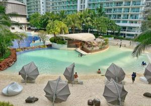 马尼拉Azure Staycation的一个带遮阳伞的游泳池,水中有人