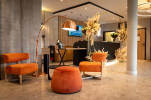 沙特尔基里亚德查尔特酒店的一个带橙色椅子、桌子和镜子的沙龙