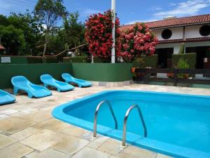 卡拉瓜塔图巴Condomínio Vila Gustavo -excelente localização的一座带蓝色座椅的游泳池,位于房子旁边