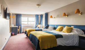 纽卡斯尔The Donard Hotel的两张位于酒店客房的床,配有蓝色窗帘