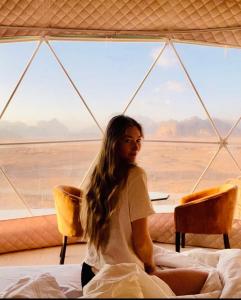 瓦迪拉姆Rum Goldeneye luxury camp的坐在帐篷里的床上的女人