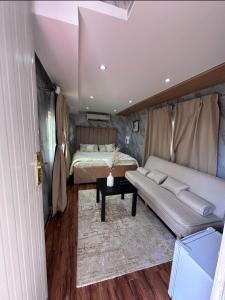 八田Hatta Farm caravan的一间卧室配有一张床、一张沙发和一张桌子