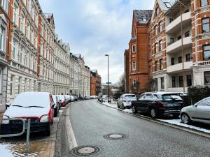基尔Exklusive Apartments in Kieler City的一条雪覆盖的街道上,路边有汽车停放