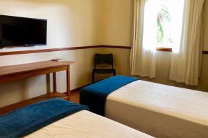 卡皮托利乌Obbá Coema Village Hotel的客房设有两张床、一张桌子和一台电视。