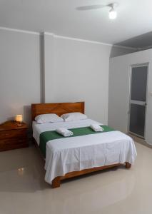 塔拉波托Humazapa的一间卧室配有一张带绿色和白色毯子的床