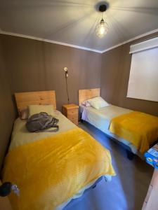 维库尼亚Cabañas Sol de Vicuña的配有黄色床单的客房内的两张床