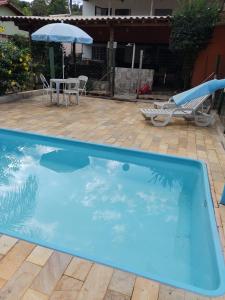 孔芬斯Sitio Cantinho da Alegria的一个带桌子和遮阳伞的大型蓝色游泳池