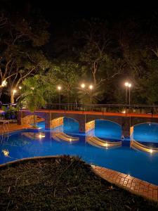 伊瓜苏港Hotel Cabañas del Leñador的夜间游泳池,有桥和灯