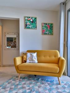 帕皮提Charmant Appartement Topaze的客厅里一张黄色的沙发,有两张照片