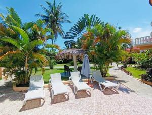 圣斐利-银港Luxury Villa Classic style - 7 min. from the beach的一组椅子、一把伞和棕榈树