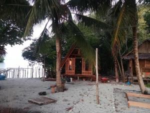 FamOr Mandira Guest House的棕榈树海滩上的小屋