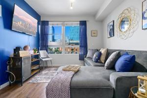 洛杉矶DTLA Escape Skyline views with luxury amenities的客厅设有灰色的沙发和蓝色的墙壁。