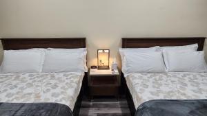 洛杉矶24 Hours Motel的一间卧室配有两张床和一张带台灯的桌子