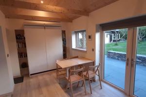 斯奇博瑞恩Cosy Cabin near Lough Hyne的一间带桌椅的用餐室和滑动玻璃门