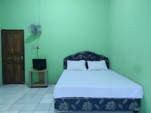 KaremaOYO 93411 Syariah Hotel Tomborang的卧室配有1张床、风扇和门