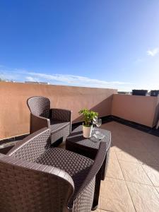 卢加Modern Spacious 2BD Penthouse with 2 Terraces - Close to Luqa Airport的阳台的天井配有2把椅子和1张桌子