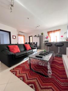 卢加Modern Spacious 2BD Penthouse with 2 Terraces - Close to Luqa Airport的客厅配有黑色沙发和红色地毯。