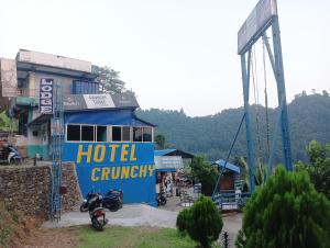 DeorāliHotel crunchy的蓝色酒店前哨,前面停有摩托车