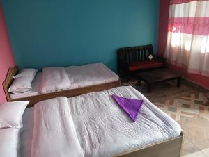 DeorāliHotel crunchy的客房内的两张床,上面有紫色的餐巾