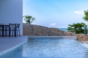 平圭卡拉夫海滩度假&Spa酒店的墙上的游泳池旁配有桌椅
