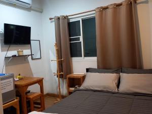 曼谷Happy Hostel的一间卧室配有一张带窗帘的床和一张书桌
