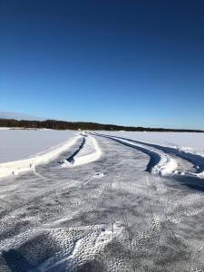 Tunnelmallinen kaksio hirsitalossa的田野上空的雪路