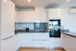 直布罗陀FORBES Suite1206-Hosted by Sweetstay的厨房配有白色橱柜和不锈钢用具