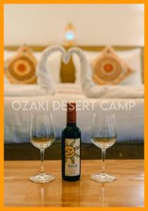 斋沙默尔Ozaki Desert Camp的桌子上放有一瓶葡萄酒和两杯酒